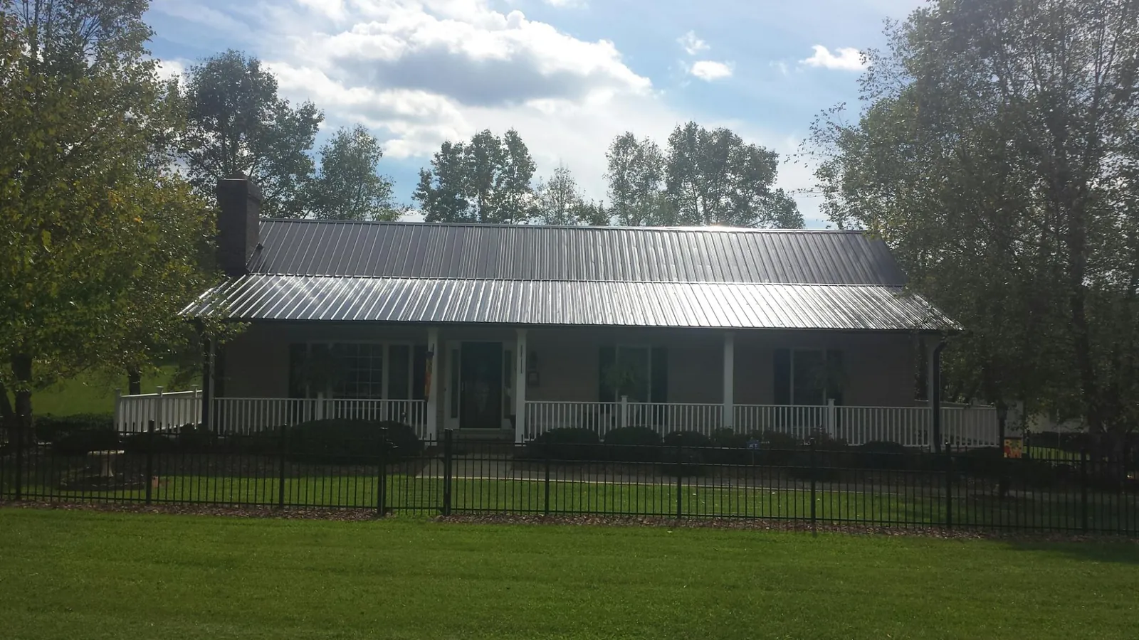 Gray metal roof on a brick ranch with a full width front porch in Glenford