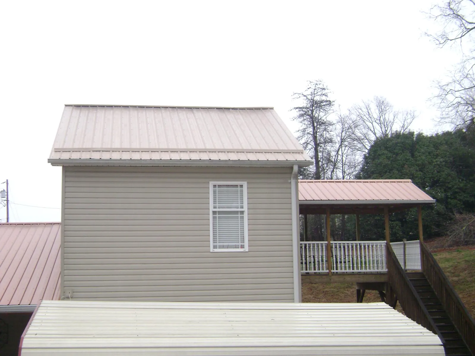 Tan metal roofs on a two story addition and attached porch, from a Roof Replacement job in Glenford